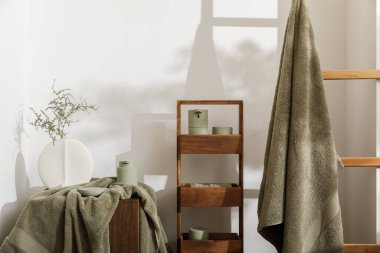 Okaliptüs yeşili gölgeli modern banyo aksesuarları. Organik pamuklu banyo havluları, sensör sabunu ve somut meşe kütüğünün üzerine losyon makinesi. Günlük vücut bakımı, spa ve sağlık banyosu konsepti