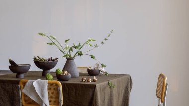 Zanaat vazosunda yeşil brunchlar, Cherimoya meyveleri, kahverengi şampiyonlar, keten masa örtüsünde seramik tabakta patlıcanlar. Yaz tatili konsepti için açık masa ayarları.