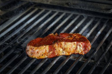  Kömür ocağında ızgarada pişirilmiş çiğ biftek ve siyah arka planda duman..