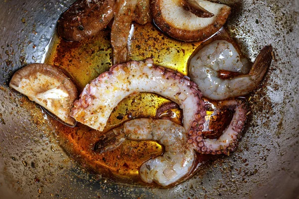 Raw seafood being marinated in metal mixing bowl. Seafood ready for grilling