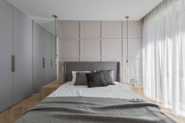 Modern minimalist bedroom interior design with grey furniture, oak floor in Scandinavian style.  Aesthetic simple interior design concept.
