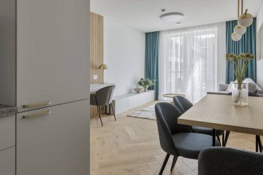 Modern minimalist kitchen and dining room interior design  with wooden furniture, oak floor. blue chairs.  Aesthetic simple interior design concept.
