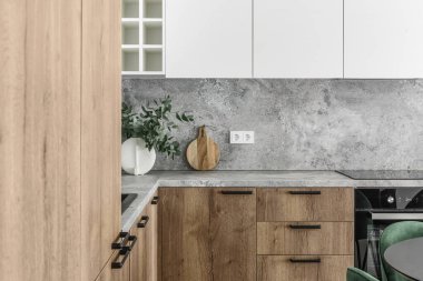 Modern minimalist mutfak ve yemek odası içi ahşap ve beyaz yüzeyler, yeşil sandalyeler ve seramik vazoda okaliptüs. Estetik basit iç tasarım konsepti.