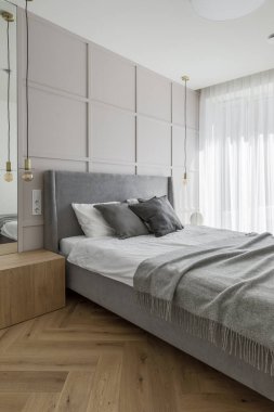 Modern minimalist bedroom interior design with grey furniture, oak floor in Scandinavian style.  Aesthetic simple interior design concept.