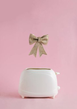 Tost makinesinden altın fiyonk çıkıyor... pembe parlak arka plan. Yaratıcı mutlu Noel kavramı. Hediye tasarımı fikri.