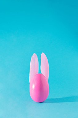 Pembe yumurtalı ve tavşan kulaklı Paskalya konsepti. Gökyüzü mavisi arka planda estetik bahar tatili tasarımı. Paskalya masası fikri
