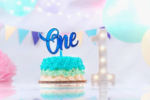 蓝色的奶昔蛋糕的第一个生日蛋糕 男孩的第一个生日装饰品 用蓝色气球装饰 1号灯装饰 图库图片