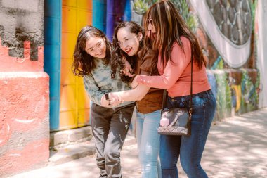 Üç genç kadın sokakta yürüyorlar, gülüyorlar, oynuyorlar ve iyi vakit geçiriyorlar..