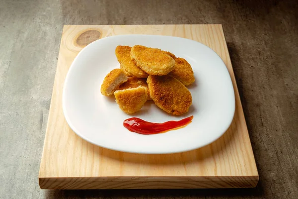 Chicken nuggets with crispy fried bread, wooden bottom. Tasty chicken nuggets. with some tomato sauce ready to eat.