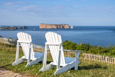 Arka planda iki Adirondack sandalyesi ve Perce Rock. Gaspe Yarımadası, Quebec, Kanada. Sandalyeler bu güzel manzarayı izlemek için konmuştu..
