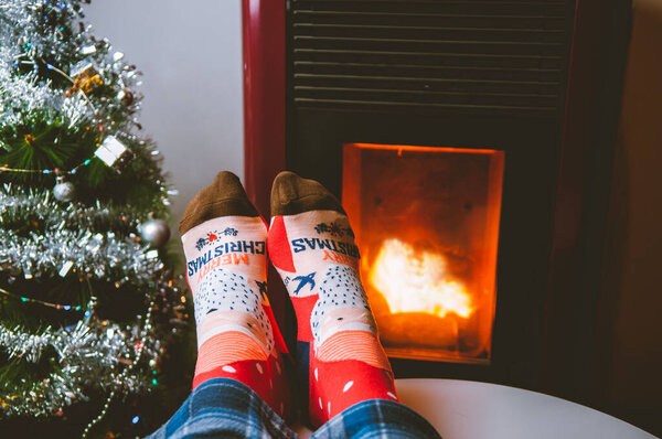 Red christmas socks with christmas message next to a fireplace and a christmas tree