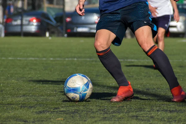 Amatör bir futbol maçında topa vurup koşan oyuncular.