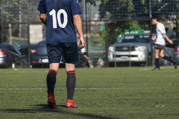 Amatör bir futbol maçında topa vurup koşan oyuncular.