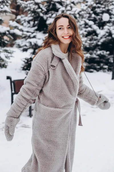 一位年轻女子穿着外套和手套 冬天愉快地在公园里散步的画像 — 图库照片