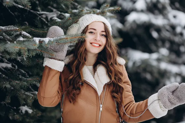 在冬季公园里穿着夹克 亮晶晶的牛仔裤和手套 头戴帽子看着相机的可爱而快乐的女孩的画像 — 图库照片