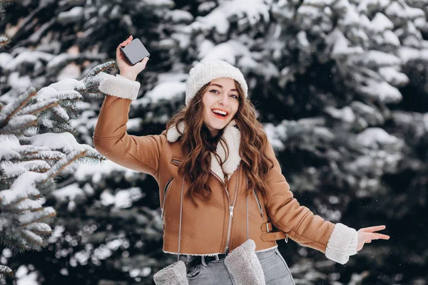 Mutlu Kız Kameraya Gülüyor Elinde Telefonuyla Kışlık Bir Parkta Kalın — Stok fotoğraf