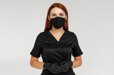 Siyah bornoz eldiven ve maske giymiş kızıl saçlı bir kadın şekerleme ustasının portresi.