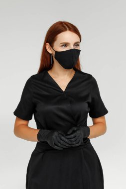 Siyah eldiven ve maske giymiş kızıl saçlı kadın şekerleme ustasının portresi.