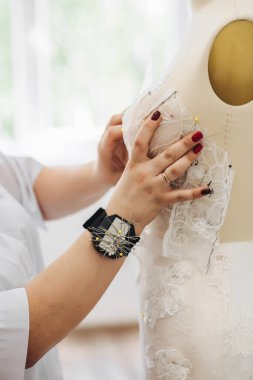 Bir kadın gelecekteki gelinlikle ilgili bir şeyler yapıyor. Elbisenin içinde bir sürü iğne var..