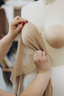 Yaratıcı bir tasarımcı mankenin kumaşını kontrol ediyor. Mankenin içinde birkaç iğne var..