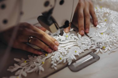 Bir tasarımcı ekipmanlı beyaz bir elbise yapıyor. Gelinlikte bir sürü sarı iğne var..