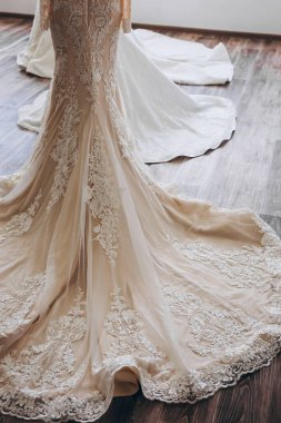 Odada uzun beyaz bir elbise var. Elbisenin arkasında iki elbise daha görüyoruz..