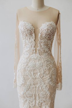 Beyaz desenli bir elbise var. Elbise gri arka planda duruyor..