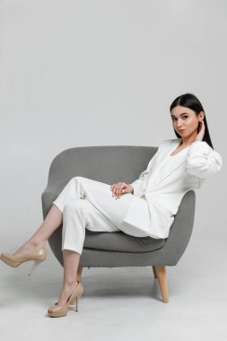 Gri koltukta gülümseyen ve kameraya bakan güzel bir iş kadınının portresi.