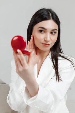 Beyaz bir fotoğraf stüdyosunda elinde aynayla poz veren güzel bir kızın portresi.