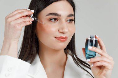 Genç ve güzel bir kozmetik uzmanının portresi. Yüzüne pipetle su koyuyor.