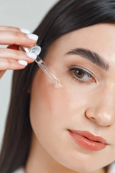 Close up portrait of a young good looking girl putting some micellar water on her face after makeup