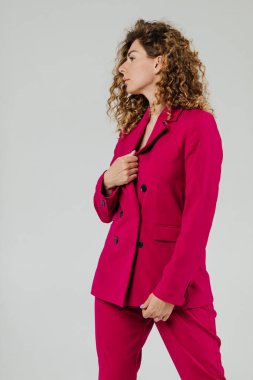 Beyaz bir duvarın önünde kırmızı takım elbiseli bir kadın modelin portresi.