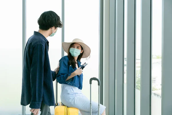 Couple talking at international airport making selfie with mobile phone and waiting for her flight at departure terminal.