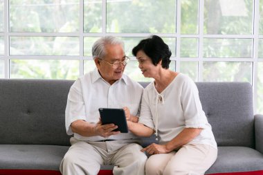 Mutlu yaşlılar dijital tableti öğrenme aracı olarak kullanıyorlar ve birlikte zaman geçiriyorlar, Asyalı üst düzey arkadaşlar evde..