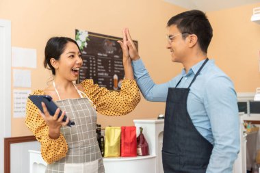 Neşeli işletme sahipleri kafelerinin önündeki tezgahın önünde birlikte dururlar..