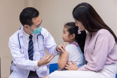 Pediyatrist doktor hastanede küçük bir kıza aşı yapıyor..