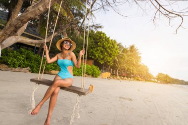 Akşam vakti tropik plajda sallanan güzel bir kadın..