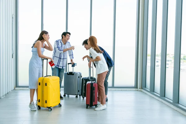 Gençler havaalanında pencerelerin yanında toplanmış arkadaşlarıyla mutlu bir gülümseme konuşuyorlar..