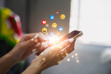 Akıllı telefon kullanıp emoji gönderen genç bir kadın. Mobil akıllı telefon, emoji emoticon mesajı gönderiyor.