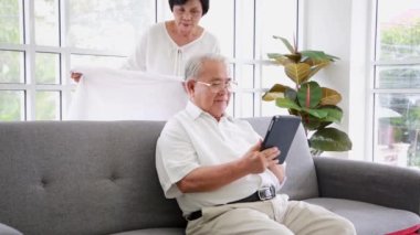 60 'lı yaşlarda yaşlı bir kadın orta yaşlı bir kocaya sarıldı ve eve battaniyeli battaniye getirdi. Mutlu yaşlı çift, rahatlayın. Oturma odasında iyi hafta sonları..