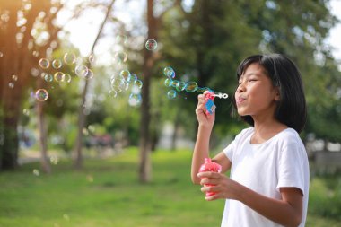 Sabun köpüğüyle oynayan mutlu kız. Parkta yürüyen aktif bir çocuk. Aile hayatı. tatil çocuğu konsepti