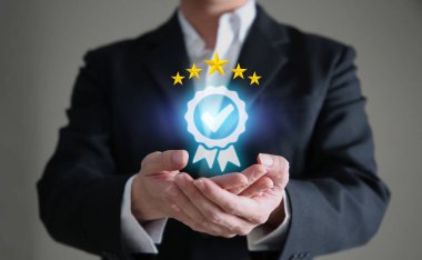 İş adamı elinde simge tutuyor. Kalite Güvence Servisi Garanti Standardı .