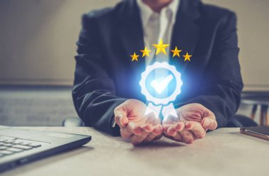 İş adamı elinde simge tutuyor. Kalite Güvence Servisi Garanti Standardı .
