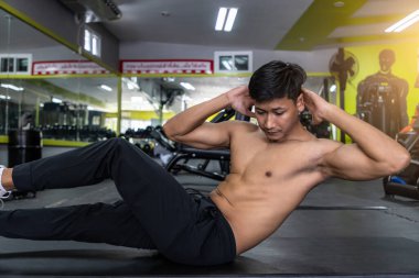 Modern spor salonunda mekik ya da mide egzersizi yapan genç bir sporcu..