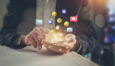 Akıllı telefon kullanarak emojileri gönderen işadamının yakın çekimi.