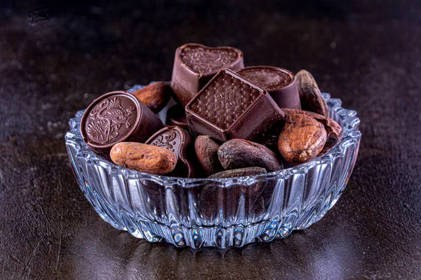 Σοκολάτες Σκαλιστό Γυάλινο Δίσκο Φωτογραφήθηκε Σκούρο Φόντο Κόκκους Κακάο — Φωτογραφία Αρχείου