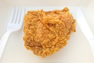 Plastik bıçak ve çatalla beyaz kağıt tabakta kızarmış tavuk..