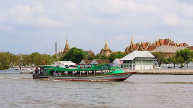 Bangkok, Tayland 3 Mart 2021 Chao Phraya Ekspres Teknesi, Büyük Saray 'ın arka planına karşı nehirde seyreden yolcularla doluydu..