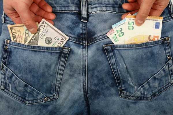 Close up man pickpocket hands pull and steal several different value US dollar and Euro paper currency banknotes from jeans back pockets, low angle view