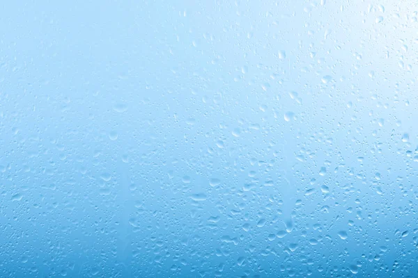 雨天关上雨滴 玻璃窗玻璃上的水在灰色和蓝色的天空背景上流动 — 图库照片